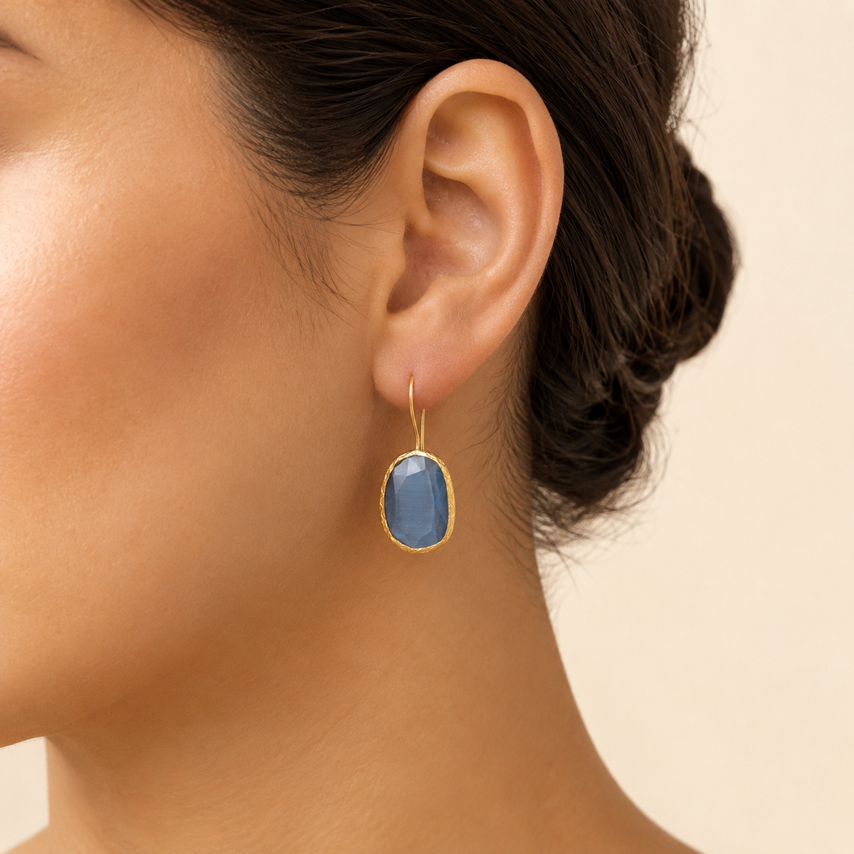 Gray teardrop earrings with a gold-plated setting on a white background.