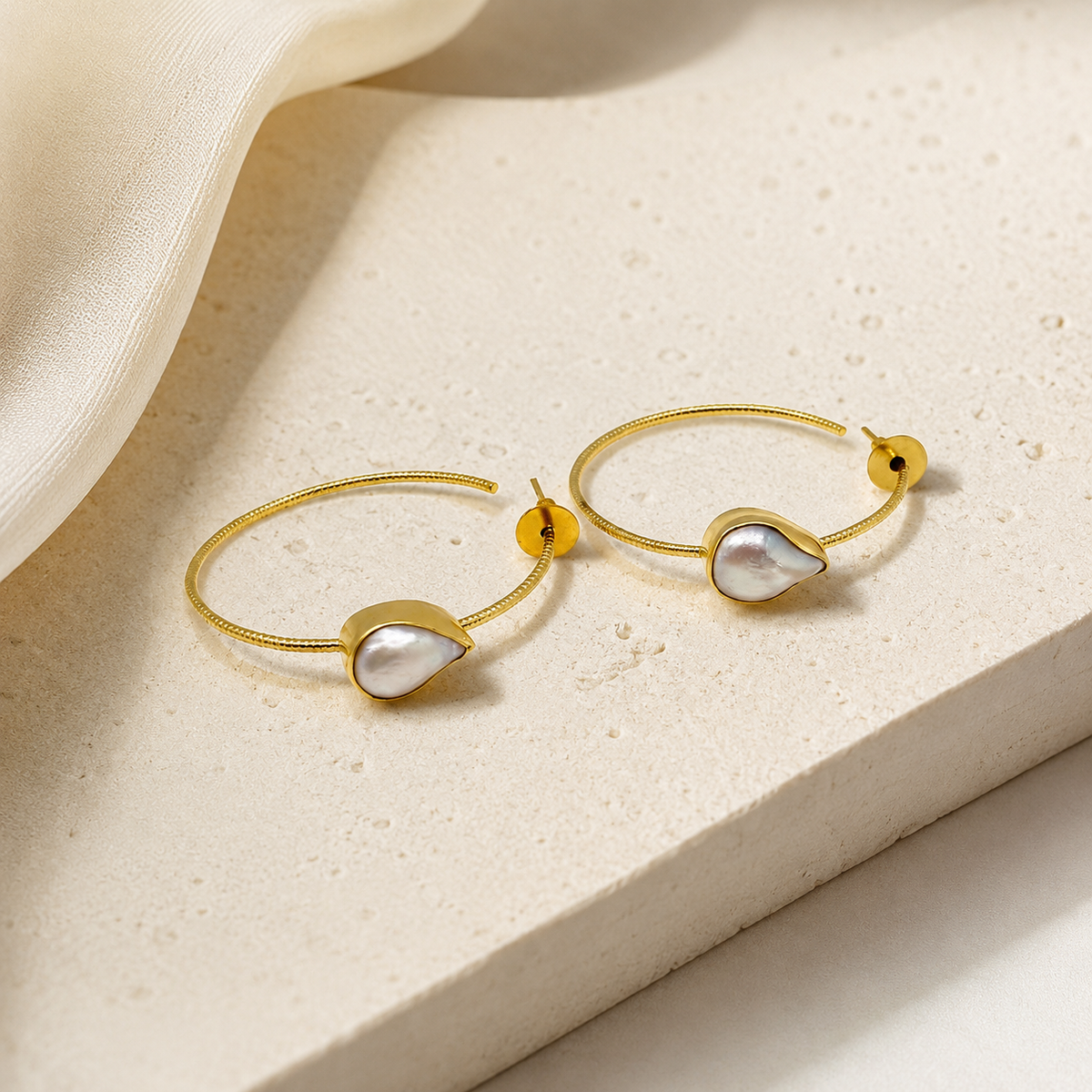 Gold-plated teardrop earrings with a soft gray stone look.