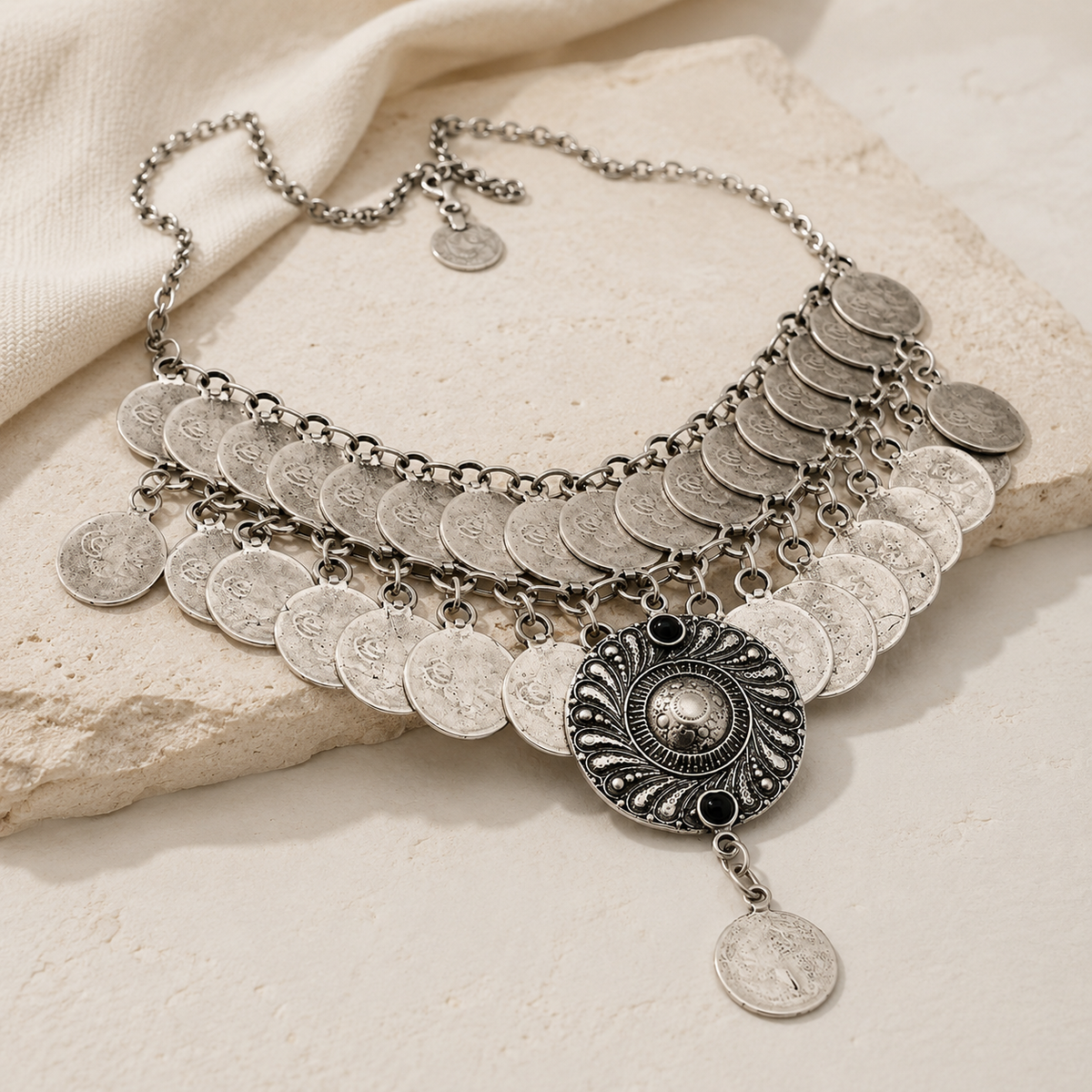 Angled view of a silver-tone layered coin necklace with drop detail.
