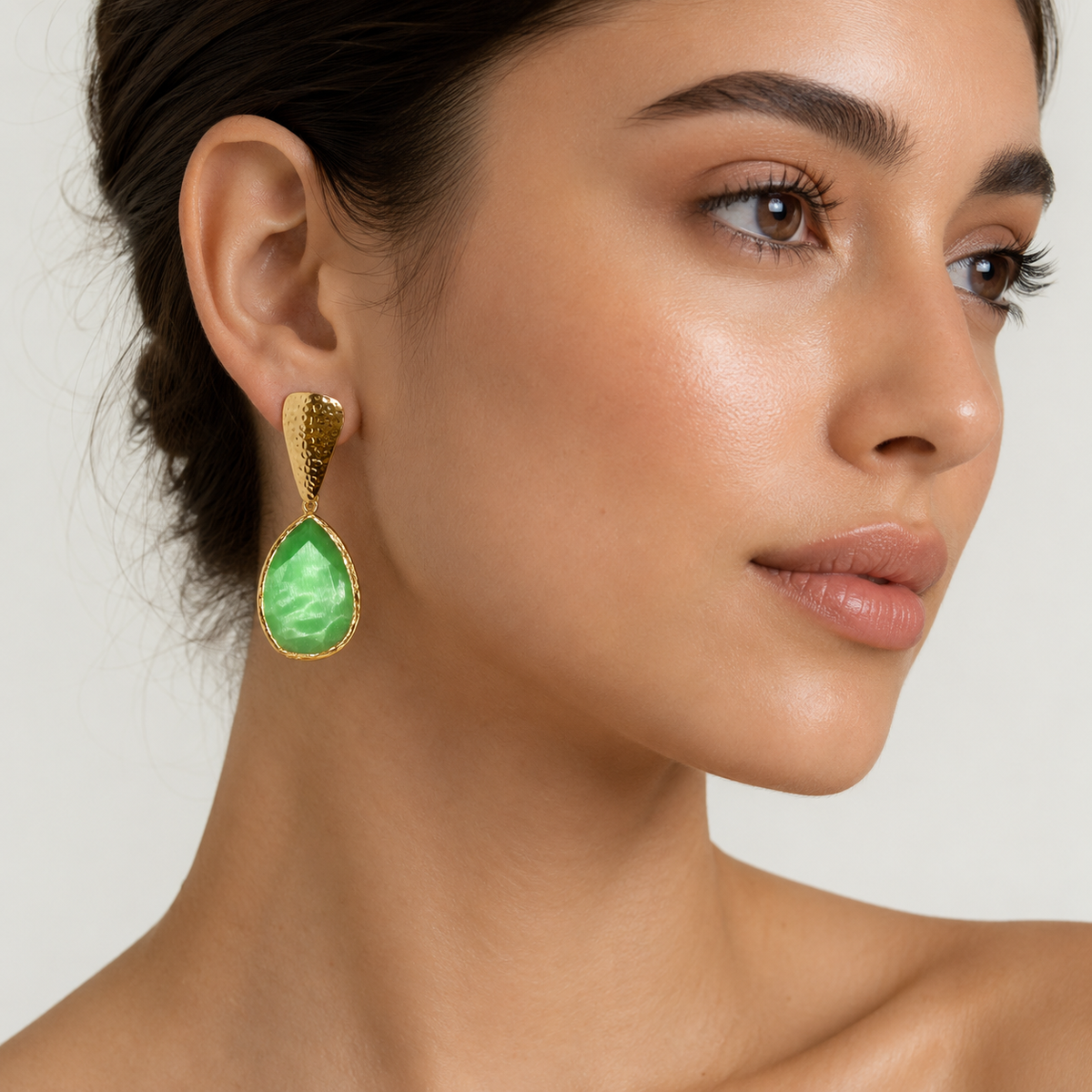 Pair of green teardrop earrings with a textured gold finish on a white background.