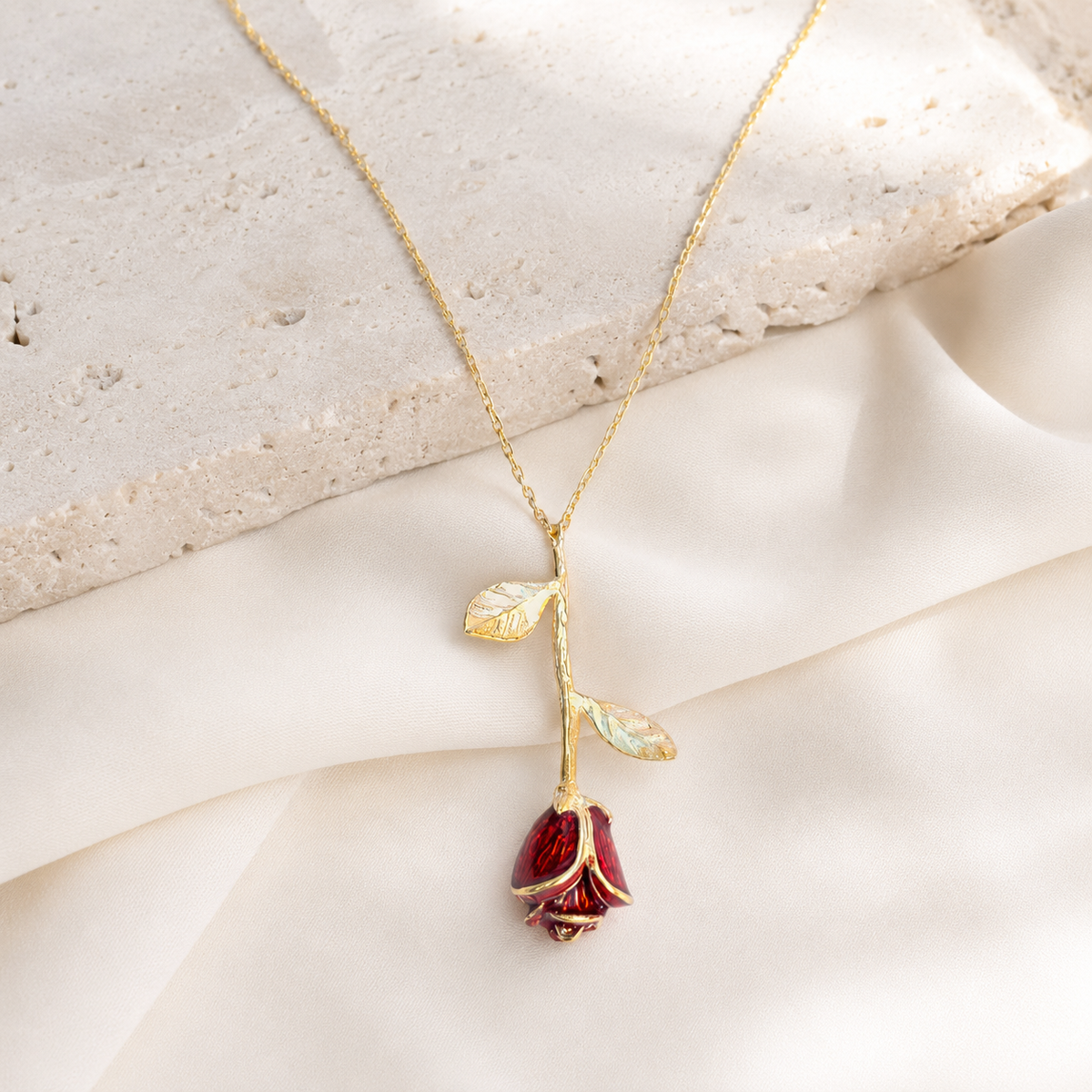 A floral pendant necklace with a gold-tone chain and red rose charm.