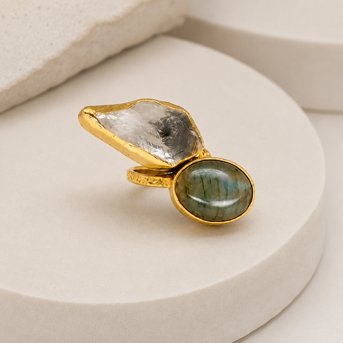 Angled view of a two-stone gold-plated ring with polished stone settings.
