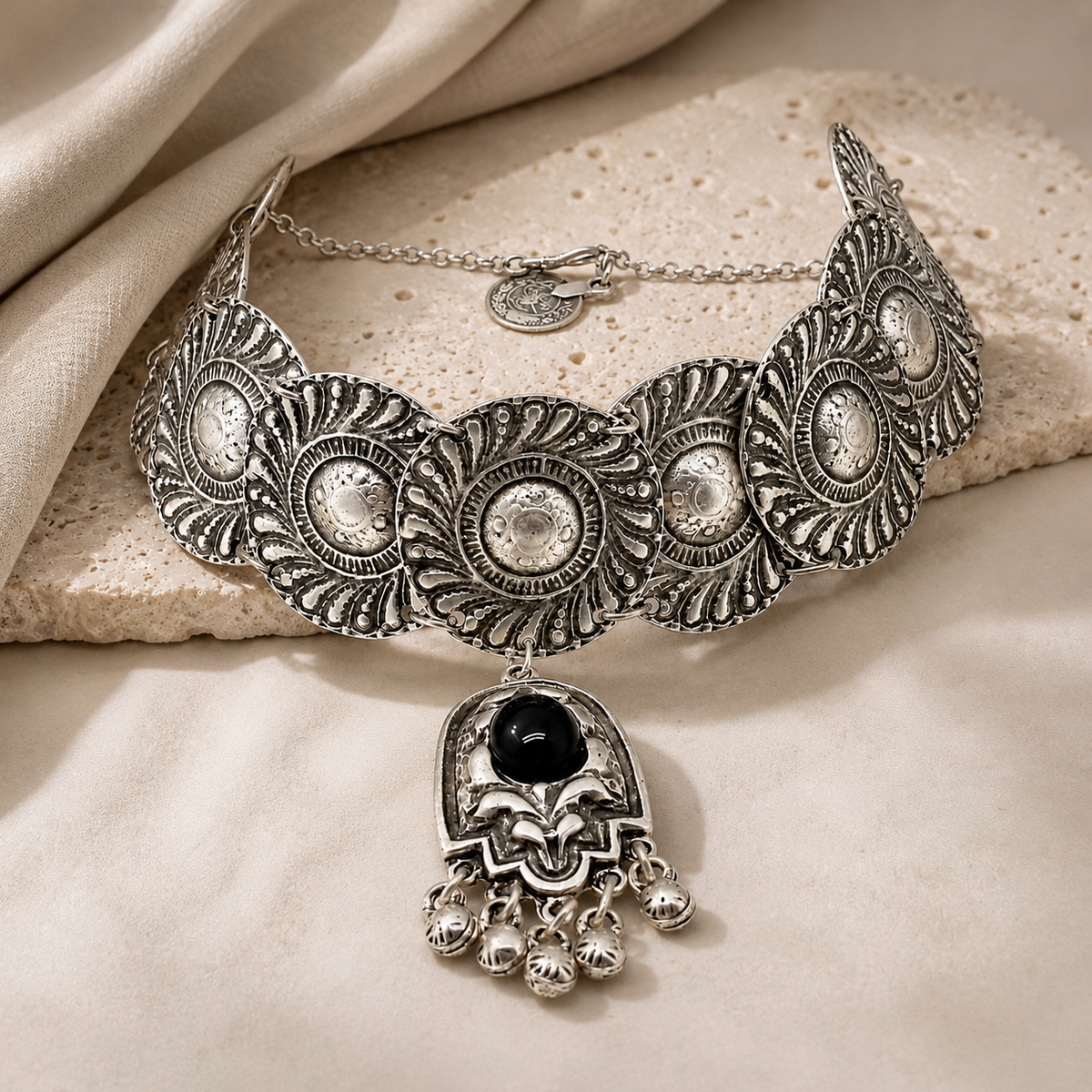 Angled view of the silver-tone choker necklace with textured discs and dangling charms.