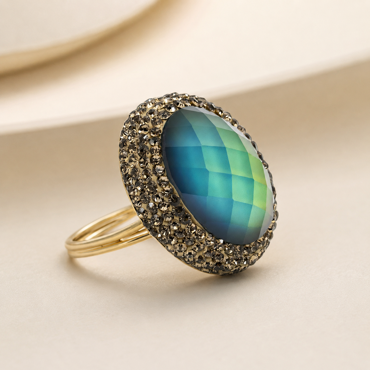 Angled view of a round color-changing ring with a faceted blue-to-green center stone and gold-tone band.