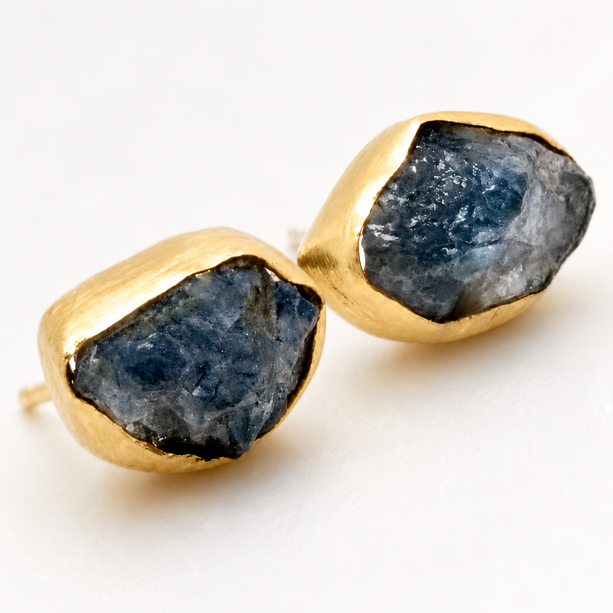 Close-up of heart-shaped stud earrings with a crystal center and gold-tone finish.