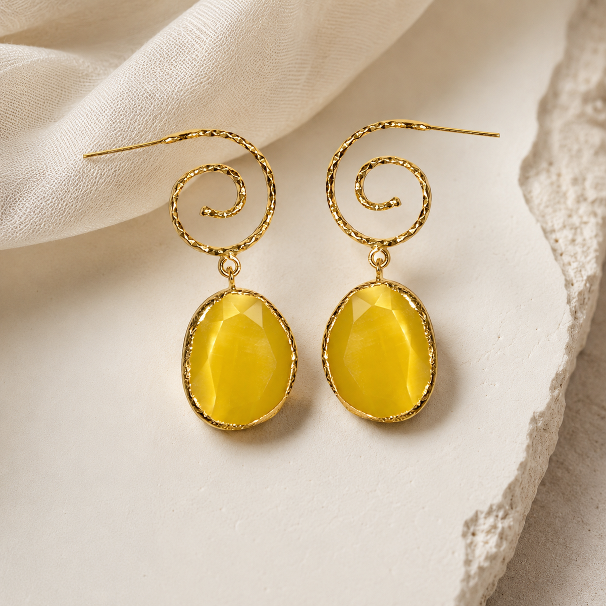 Gold-plated spiral drop earrings with bright yellow oval stones on a white background.
