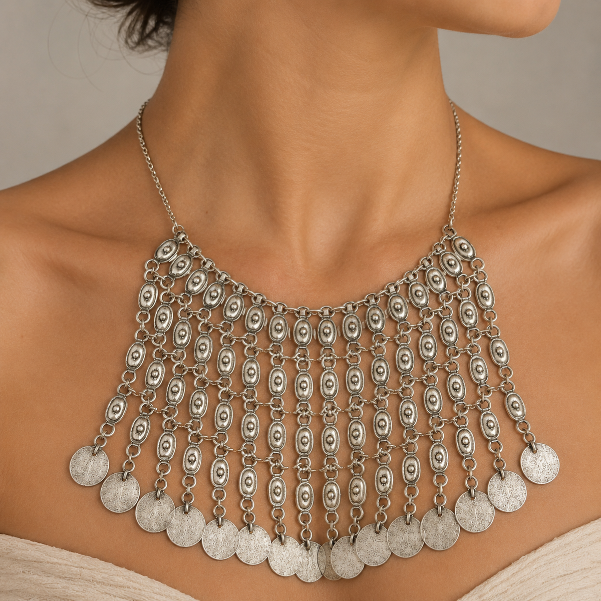 Silver-tone necklace with layered oval links and dangling coin details.