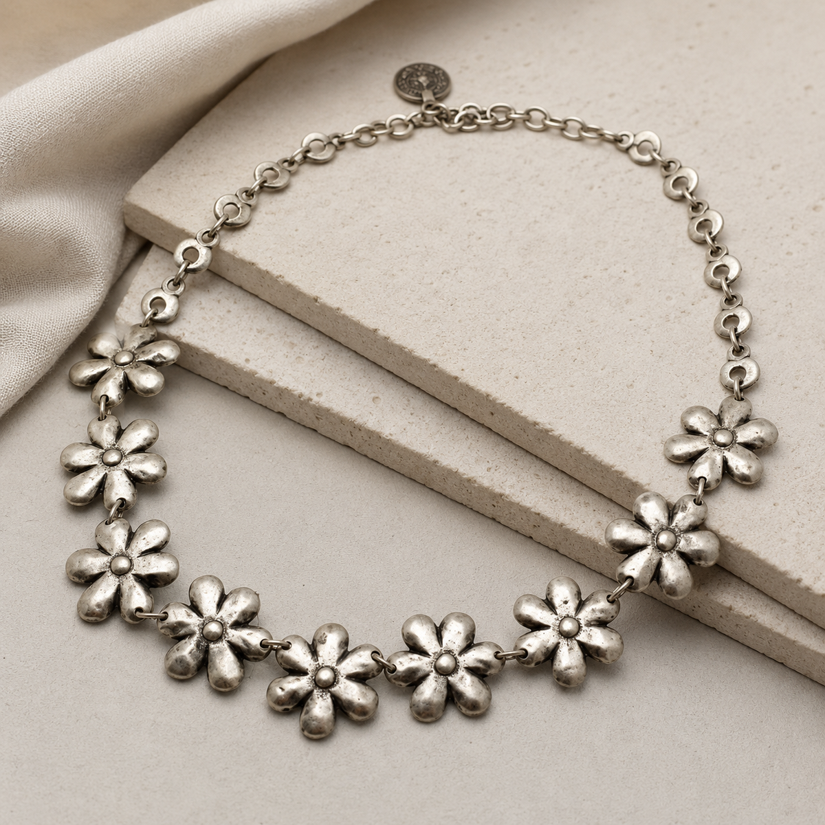 Angled view of a silver-tone necklace with flower-shaped links.