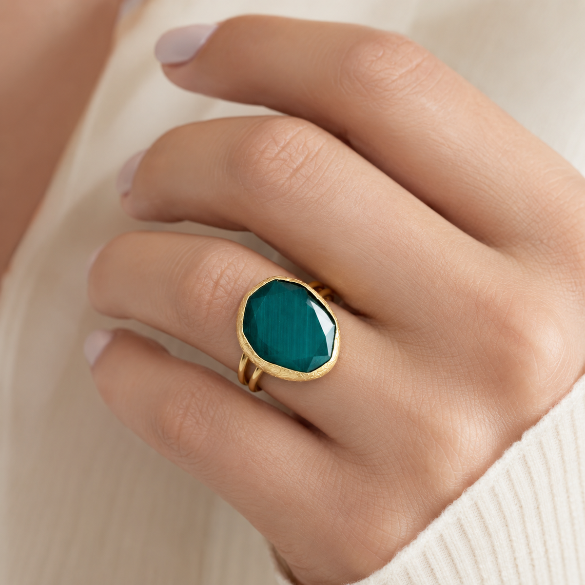 Gold-tone ring with a large green faceted stone shown on a white background.