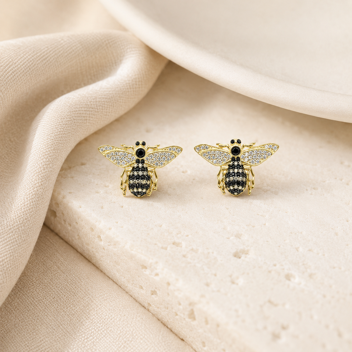 Bee-inspired stud earrings with black CZ accents and a gold-plated finish on a white background.