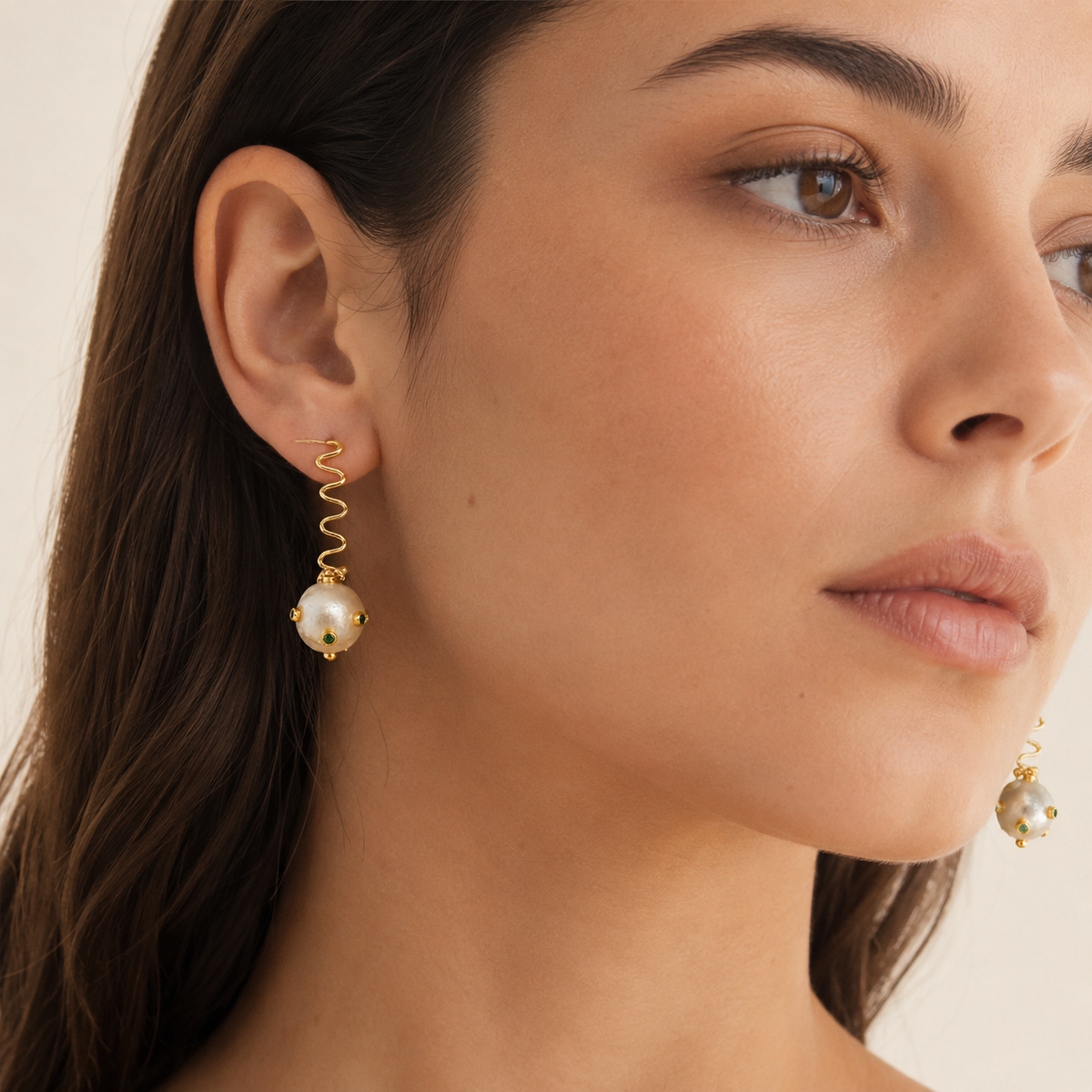Gold-plated drop earrings with a sculptural wavy shape and pearl-like ball detail.