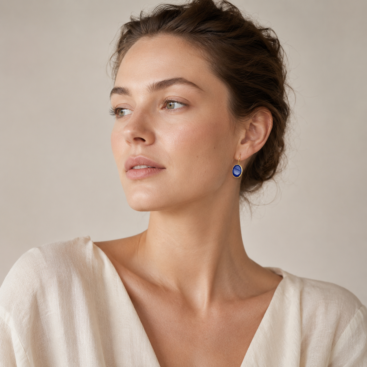 Gold-plated drop earrings with deep blue faceted stones in a clean studio image.