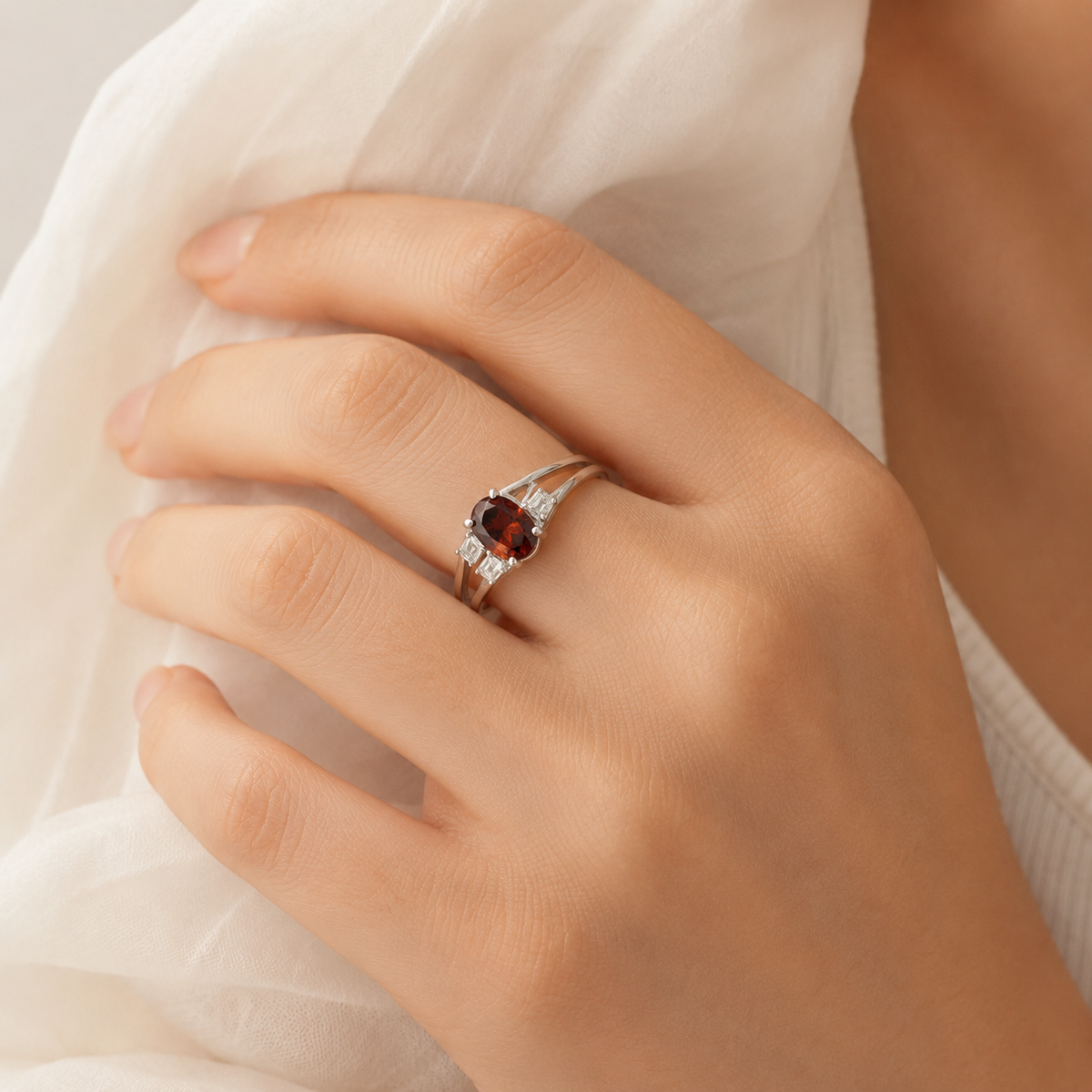 A silver-tone ring with a deep ruby stone shown on a white background.