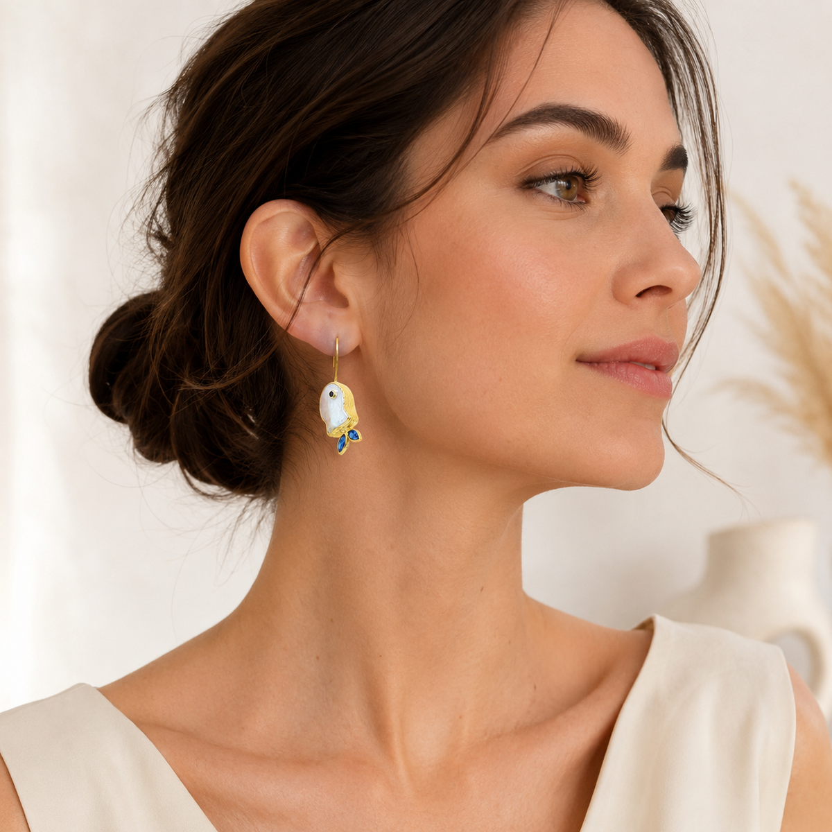 Gold-plated fish earrings with pearl-like centers and deep blue details.
