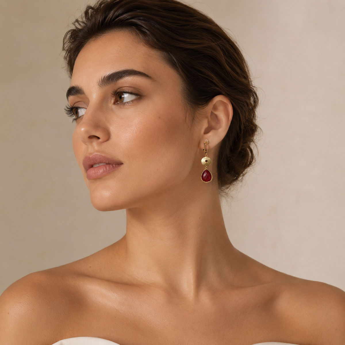 Long gold-plated statement earrings with textured links and deep red pendants on a model.