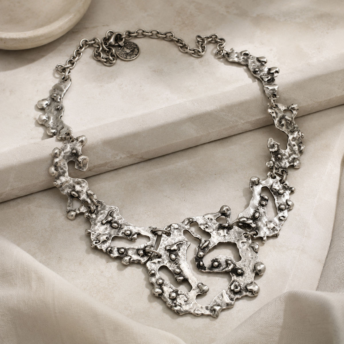 Angled view of the organic silver-tone statement necklace with irregular pendant links.