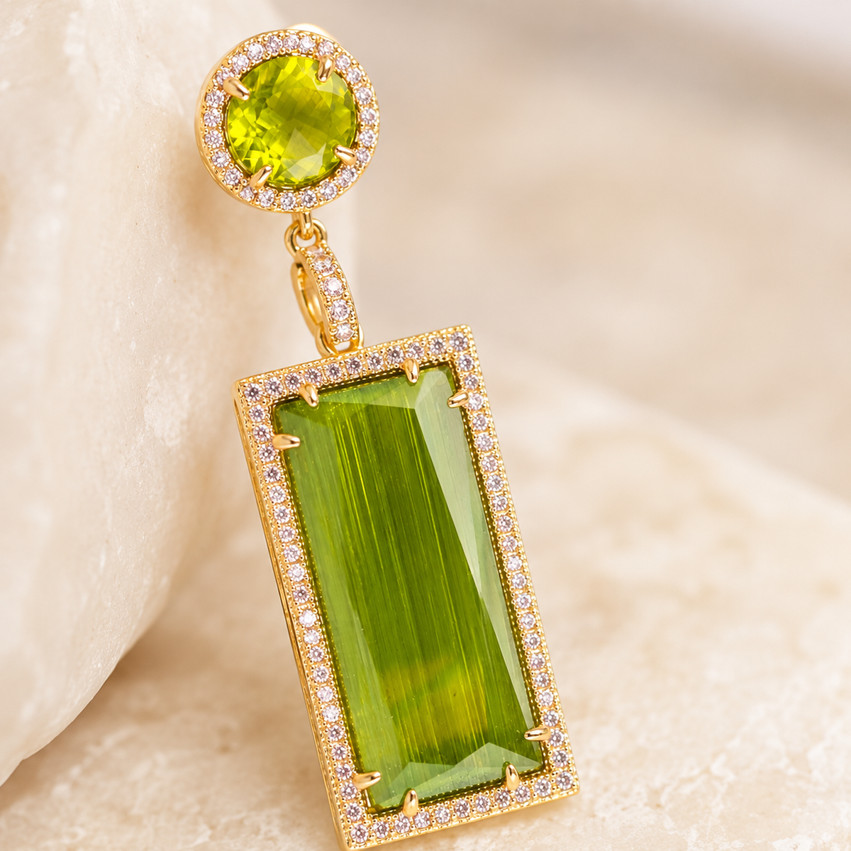 Close view of olive green stones set in a gold-plated pavé-style frame.