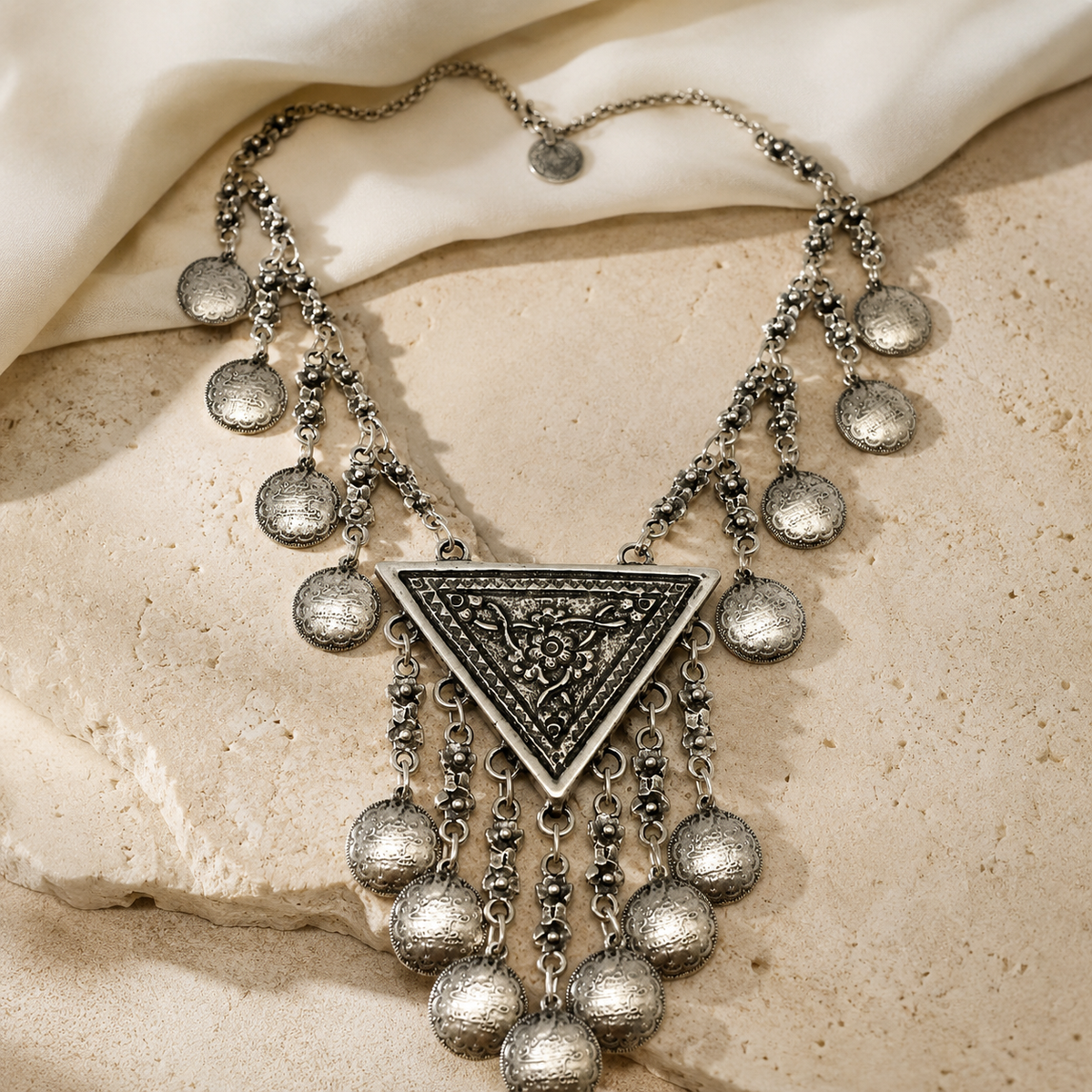 Silver-tone statement necklace with a crescent shape and dangling coin fringe.
