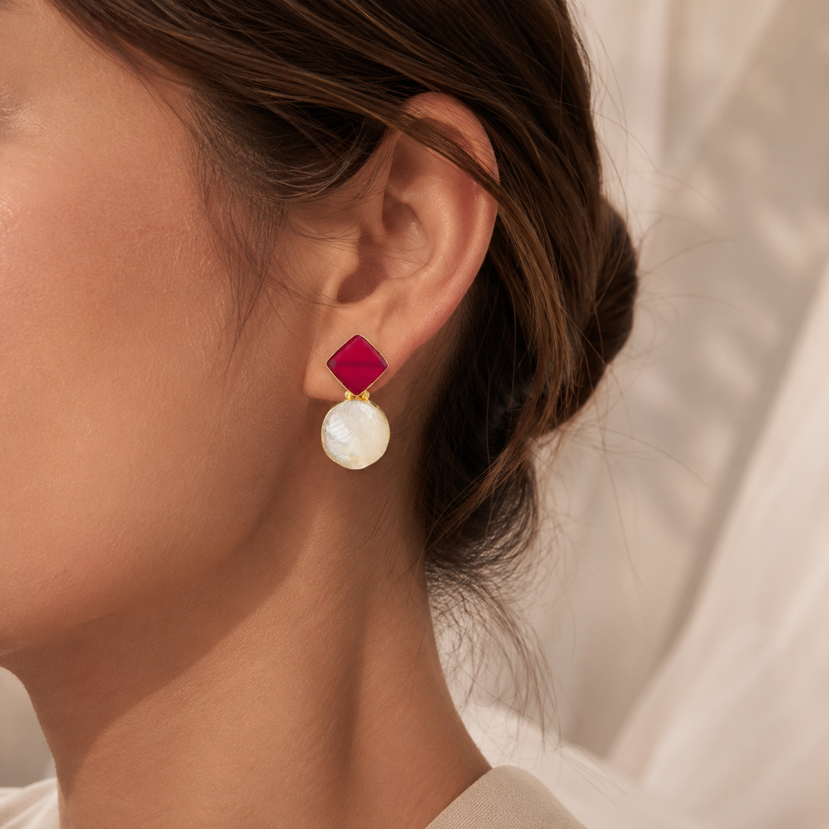 Pair of gold-plated drop earrings with red and clear stone-like accents.