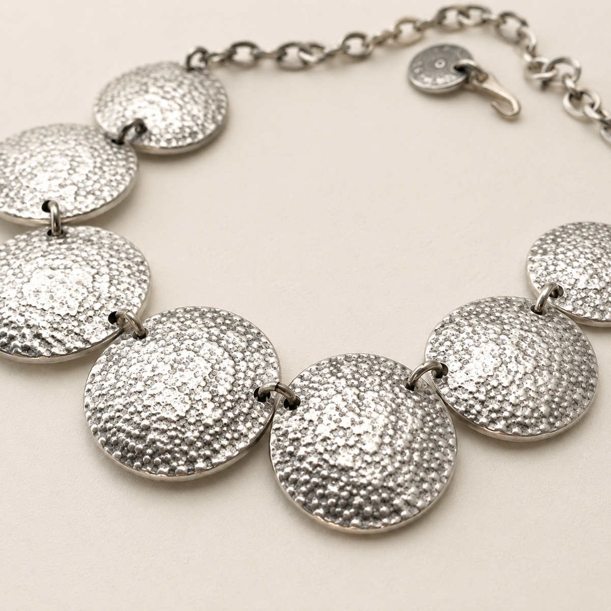 Close view of the textured hammered disc details on the necklace.