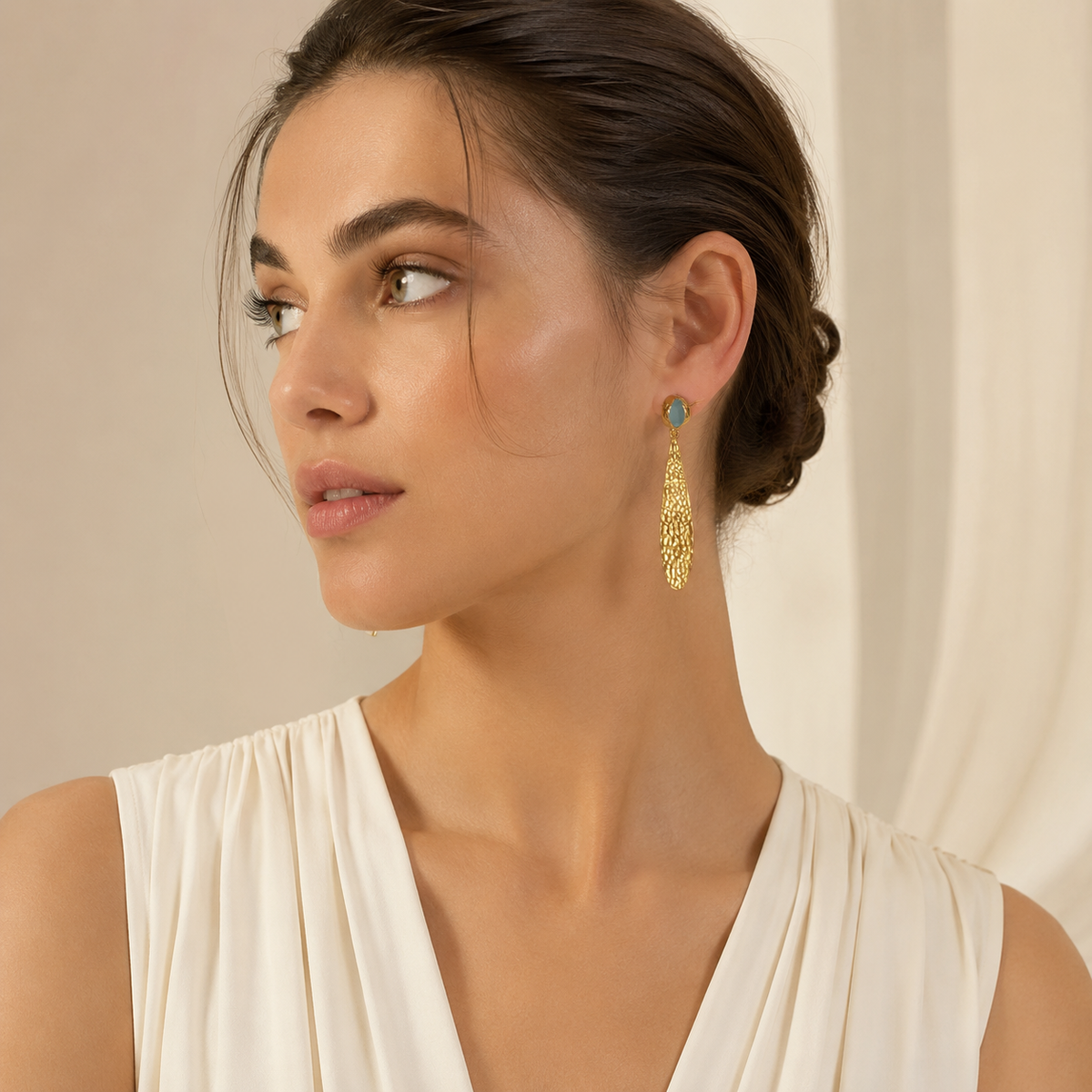 Hammered gold-plated drop earrings with textured pendants and soft blue oval accents.