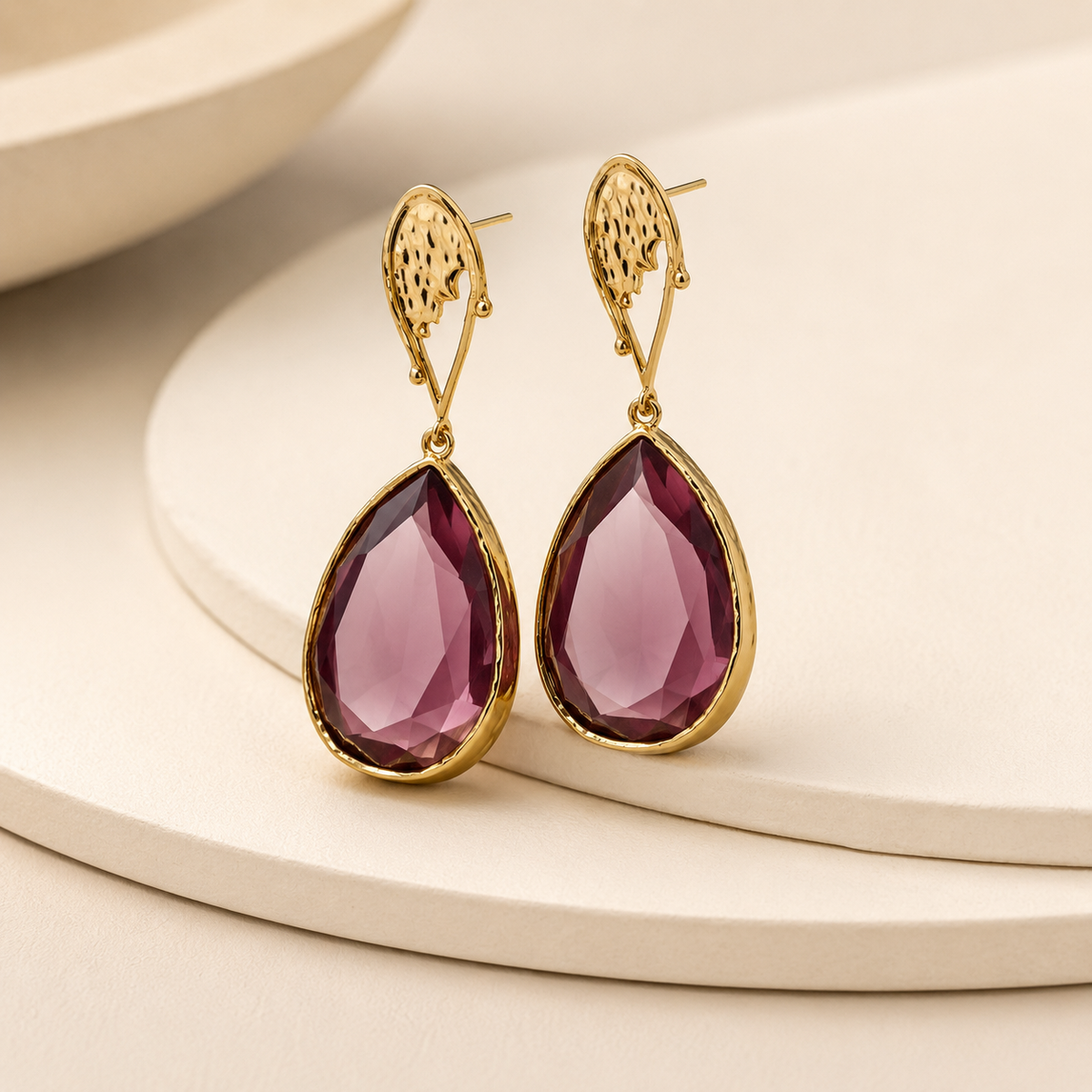 Angled view of a purple raindrop drop earring with gold-plated detail.