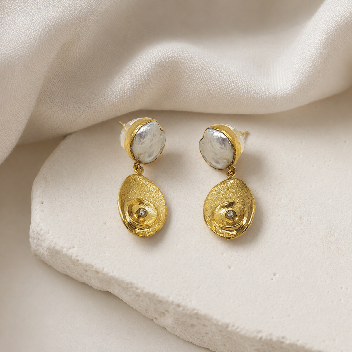 Gold-plated drop earrings with a sculptural oval shape.