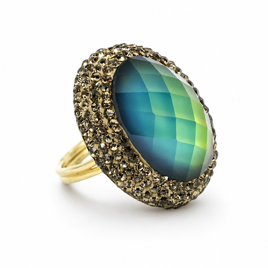 Round color-changing ring with a faceted blue-to-green center stone and a sparkling gold-tone halo.