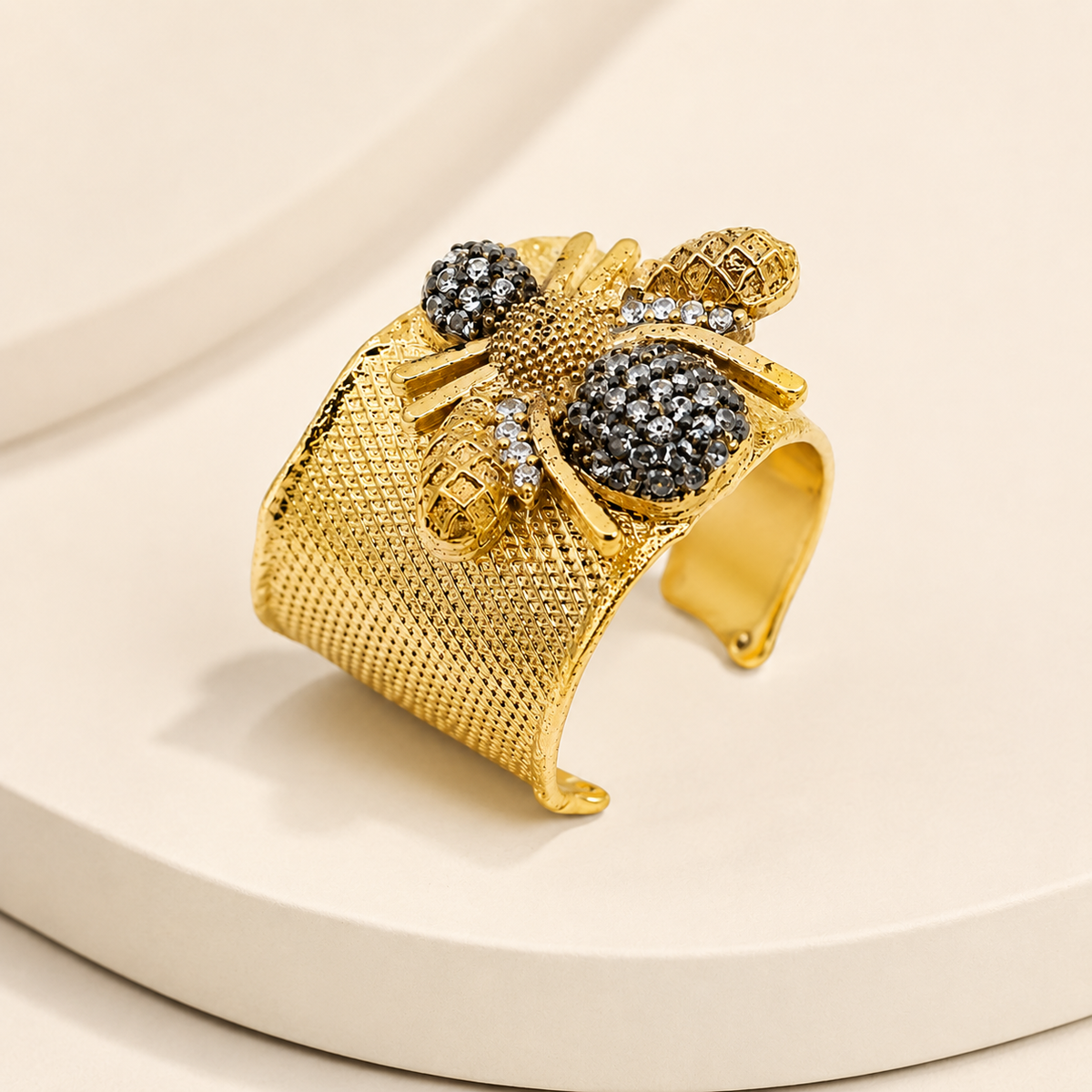 Angled view of a gold-plated wide cuff ring with CZ details and a bee design.