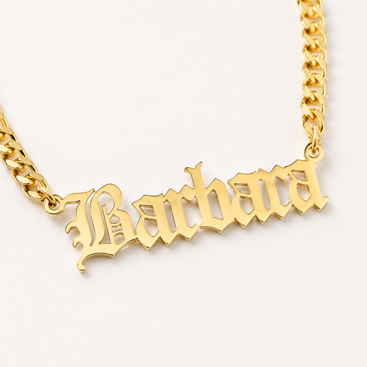Close view of the engraved name pendant and chain links in a gold-tone finish.