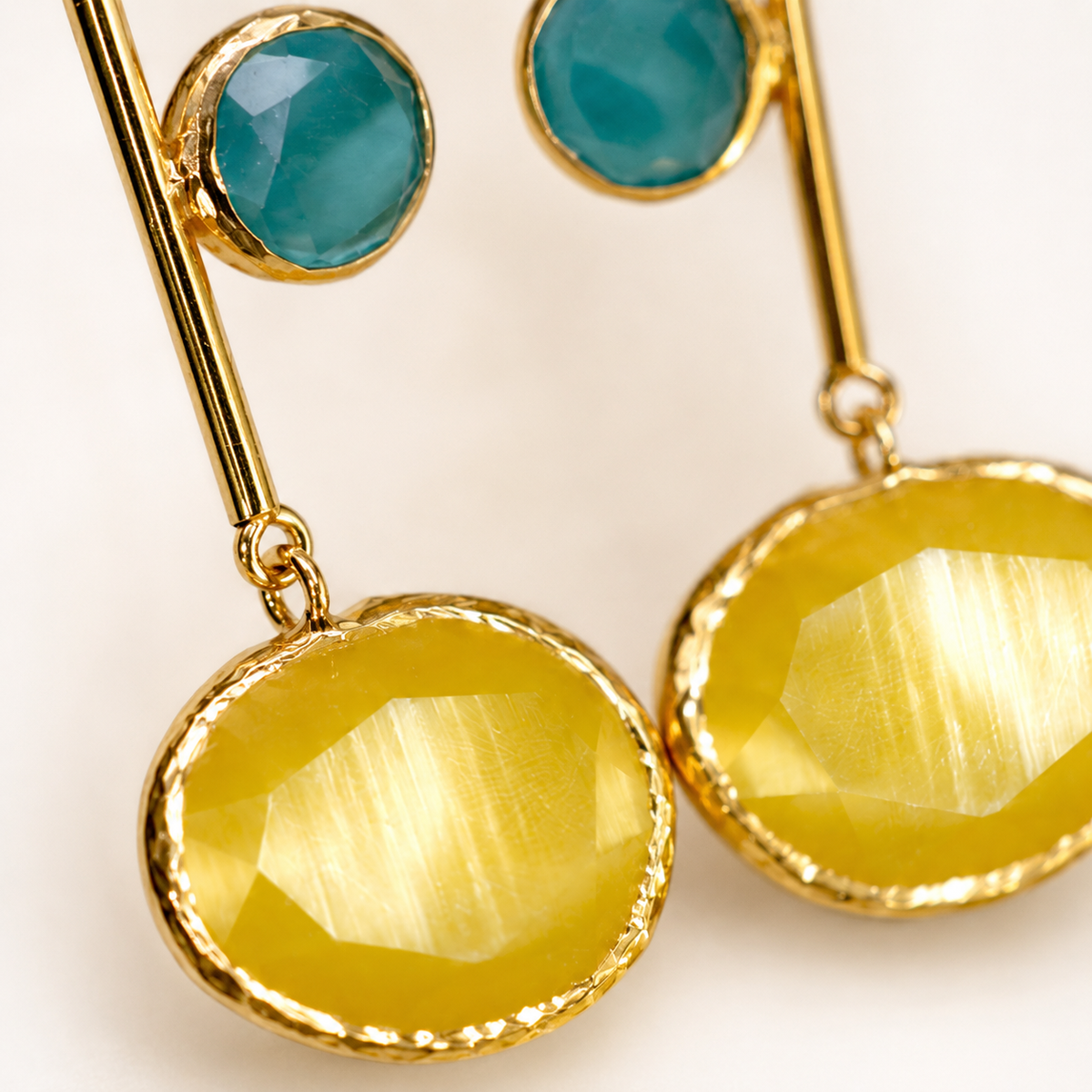Close view of mustard yellow faceted drops and polished gold-tone details.