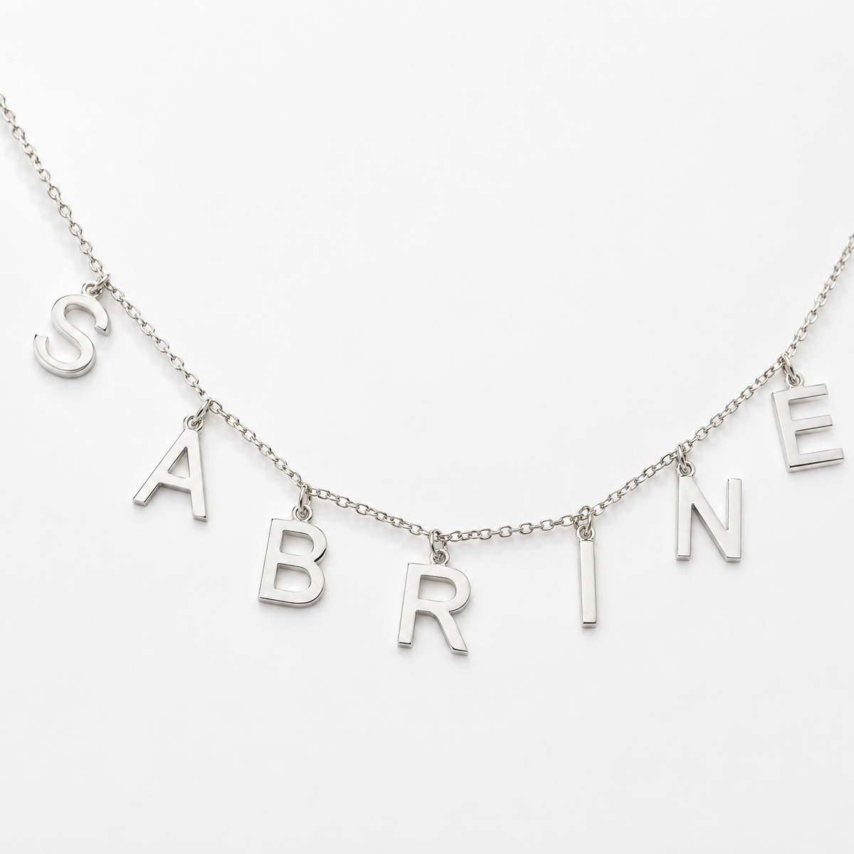 Close view of the polished letter charms and delicate chain details.