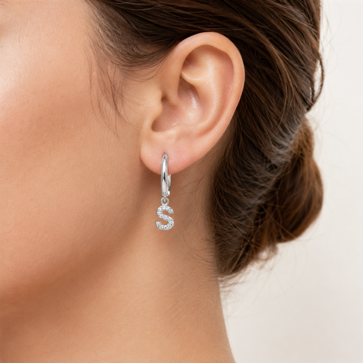 Silver-tone personalized huggie earrings with a sparkling initial charm.