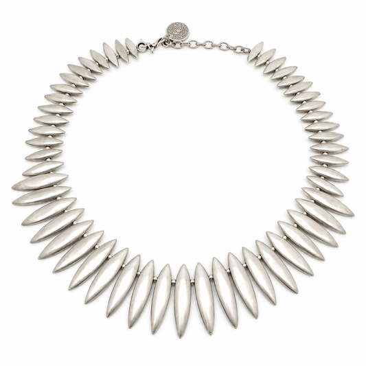 Silver-tone collar necklace with leaf-shaped spike links arranged in a sculptural curve.