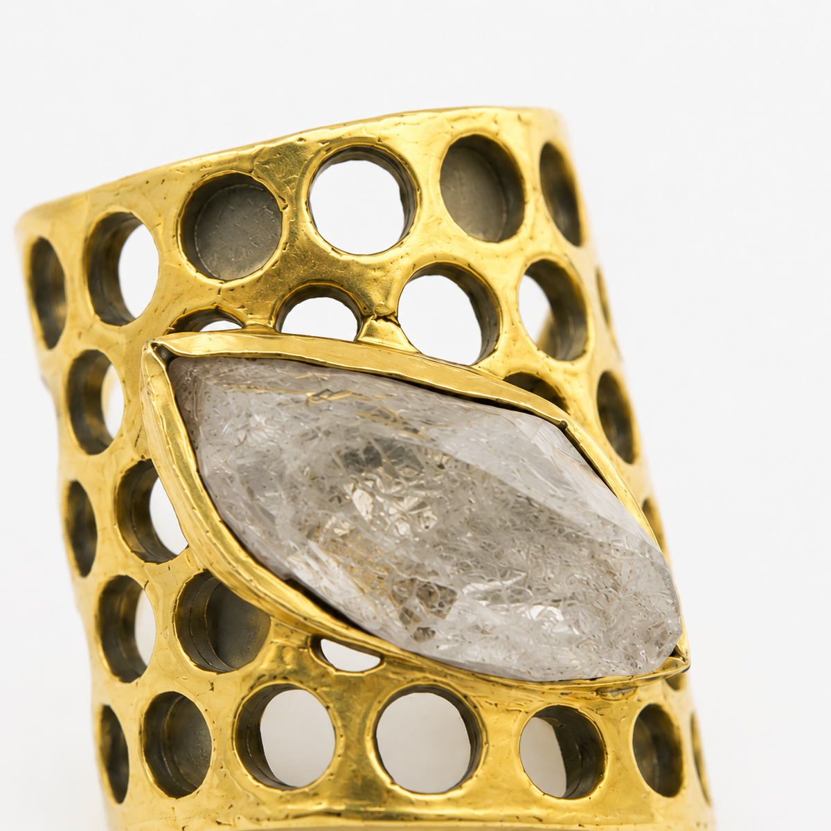 Close-up of a clear quartz statement ring with a gold-plated honeycomb pattern.