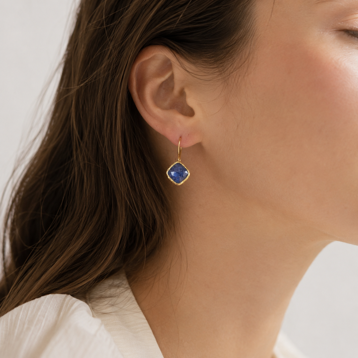 Blue sapphire dangle earrings with a gold-plated frame shown from the front.