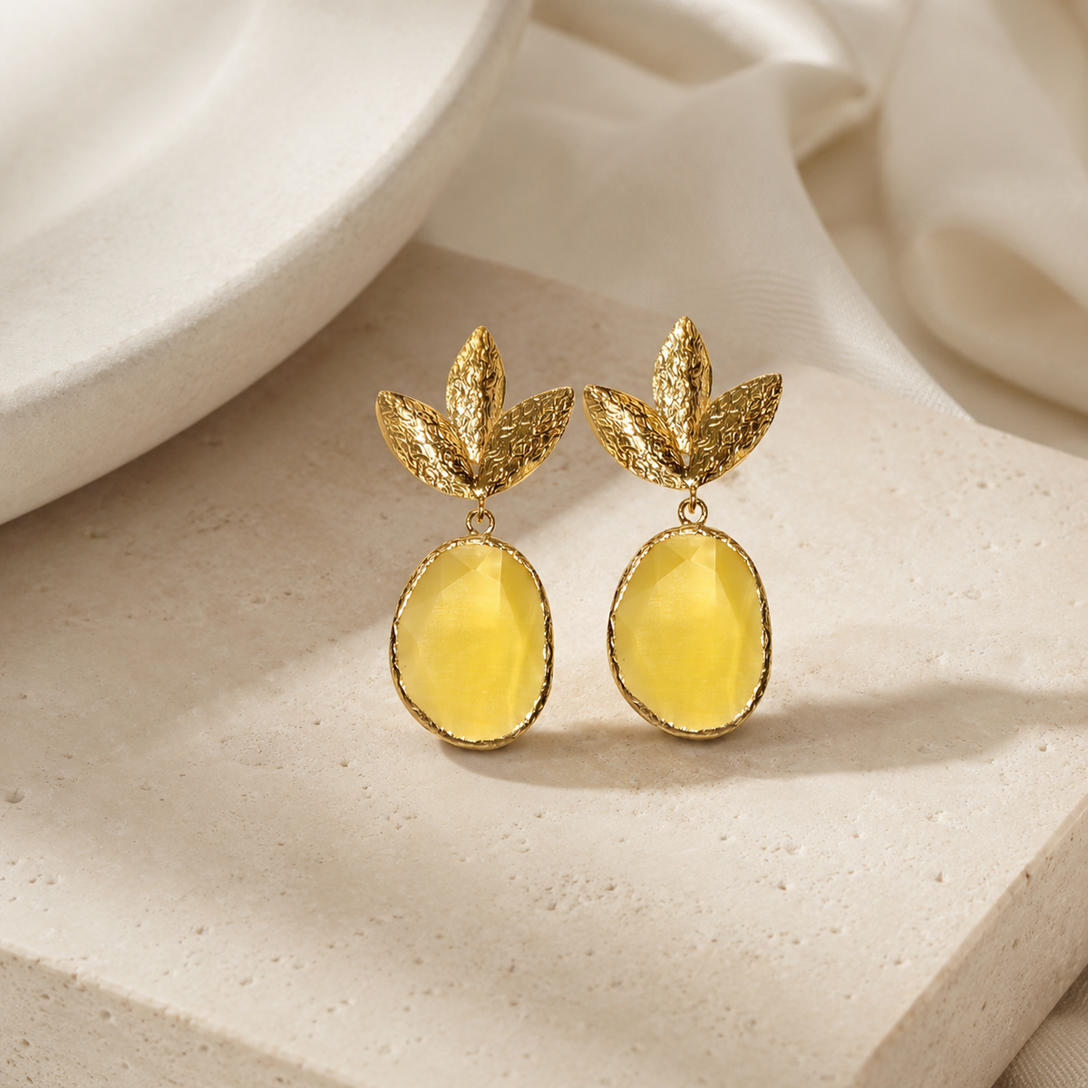 Gold tone drop earrings with leaf details and a bright yellow oval accent.