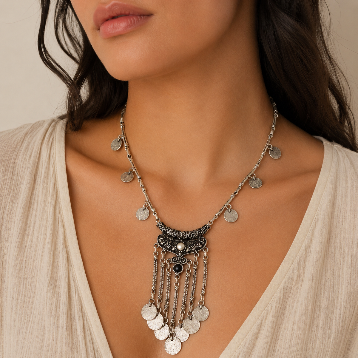 Silver-tone necklace with coin pendants, a black stone center, and tassel drops.
