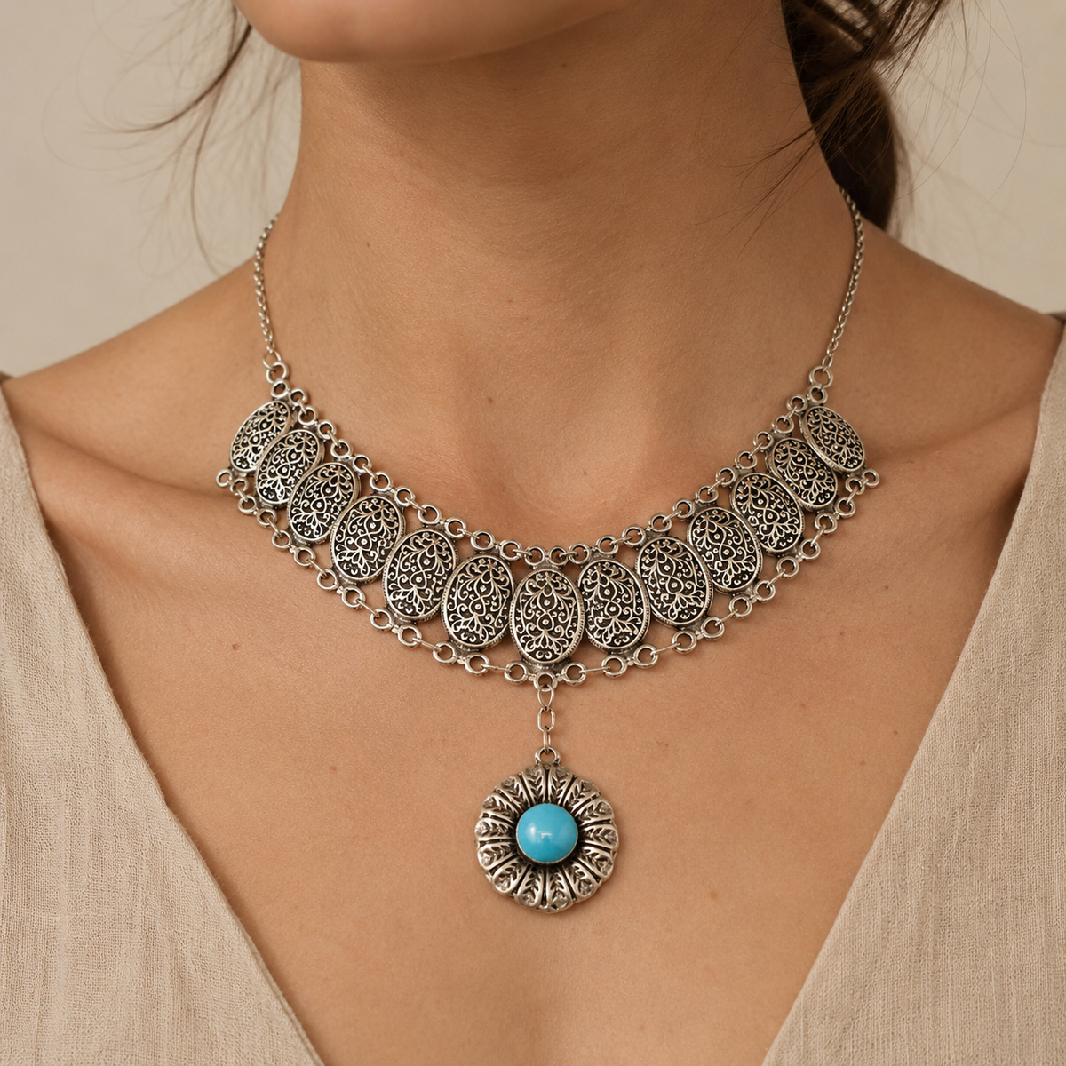 Silver-tone filigree medallion necklace with a bright turquoise pendant.