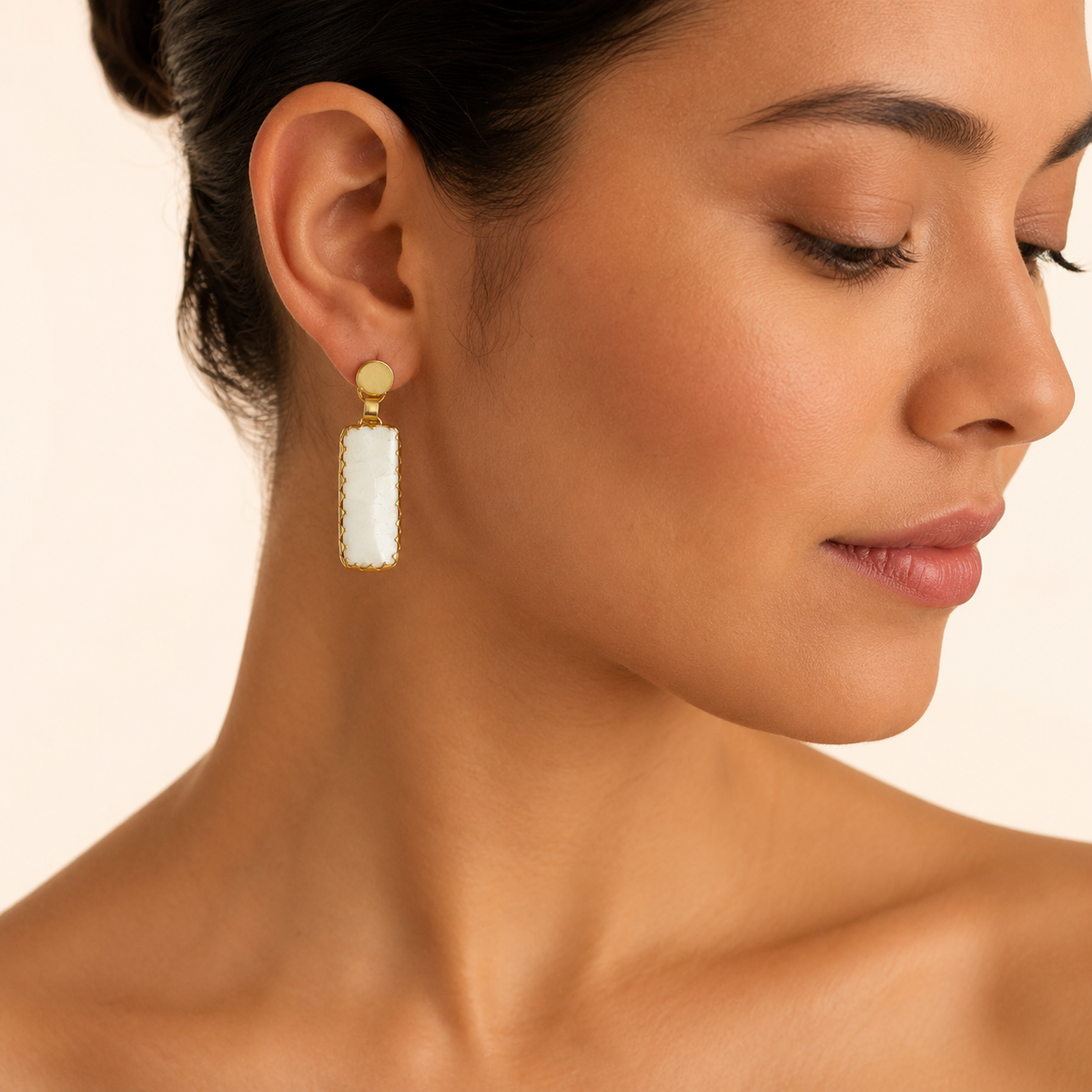 Gold-plated drop earrings shown from the front with a polished round top and rectangular stone-like drops.