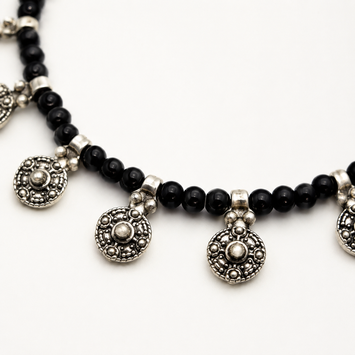 Close view of the black beads and detailed oval charm pendant accents.