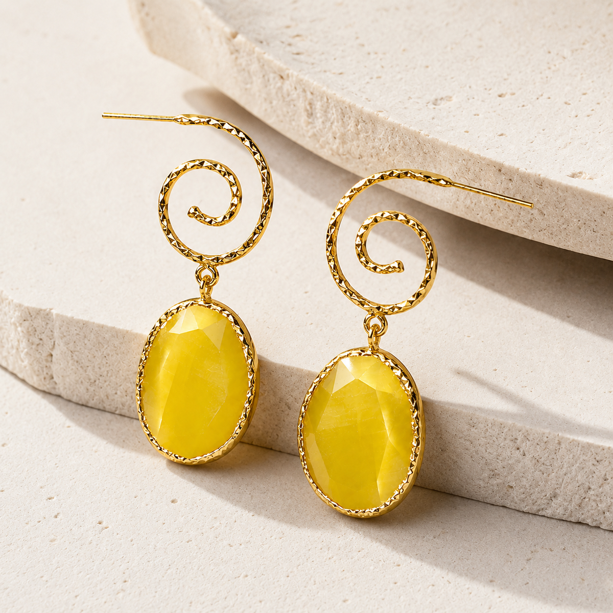 Angle view of yellow spiral gold-plated drop earrings with oval faceted drops.