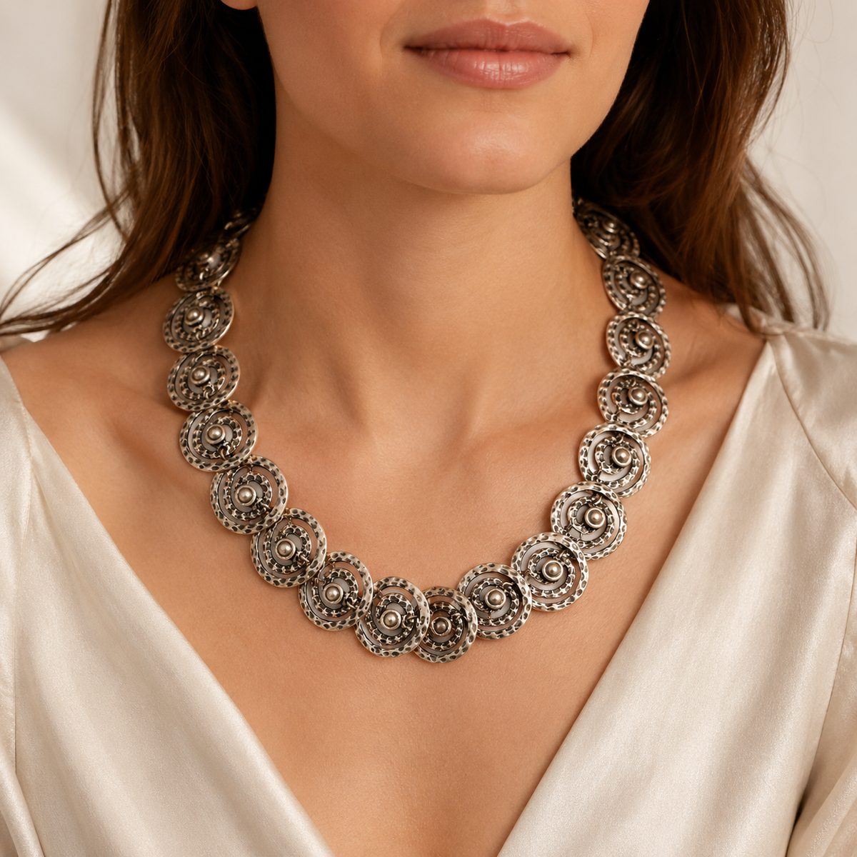 Silver-tone spiral disc statement necklace shown from above on a light background.