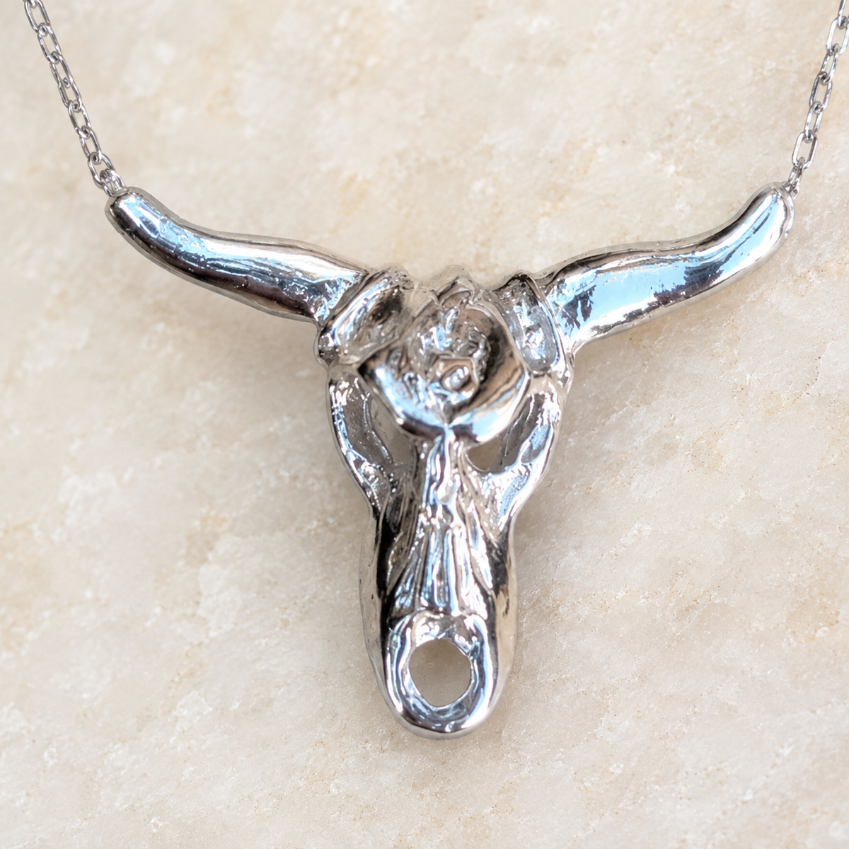 Close view of the sculptural longhorn pendant and fine chain.