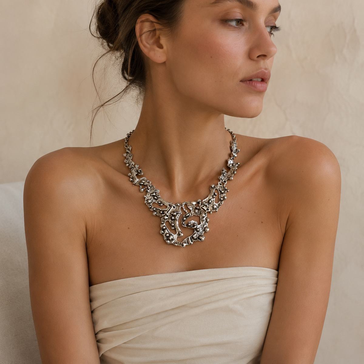 Organic silver-tone necklace with a bold pendant and textured surface.