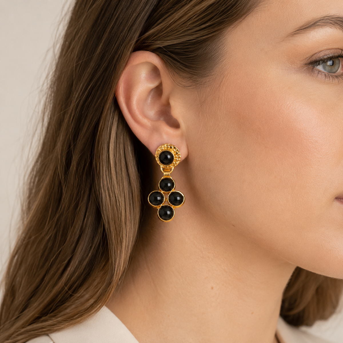 Gold-plated dangle earrings with glossy black onyx stones shown from the front.