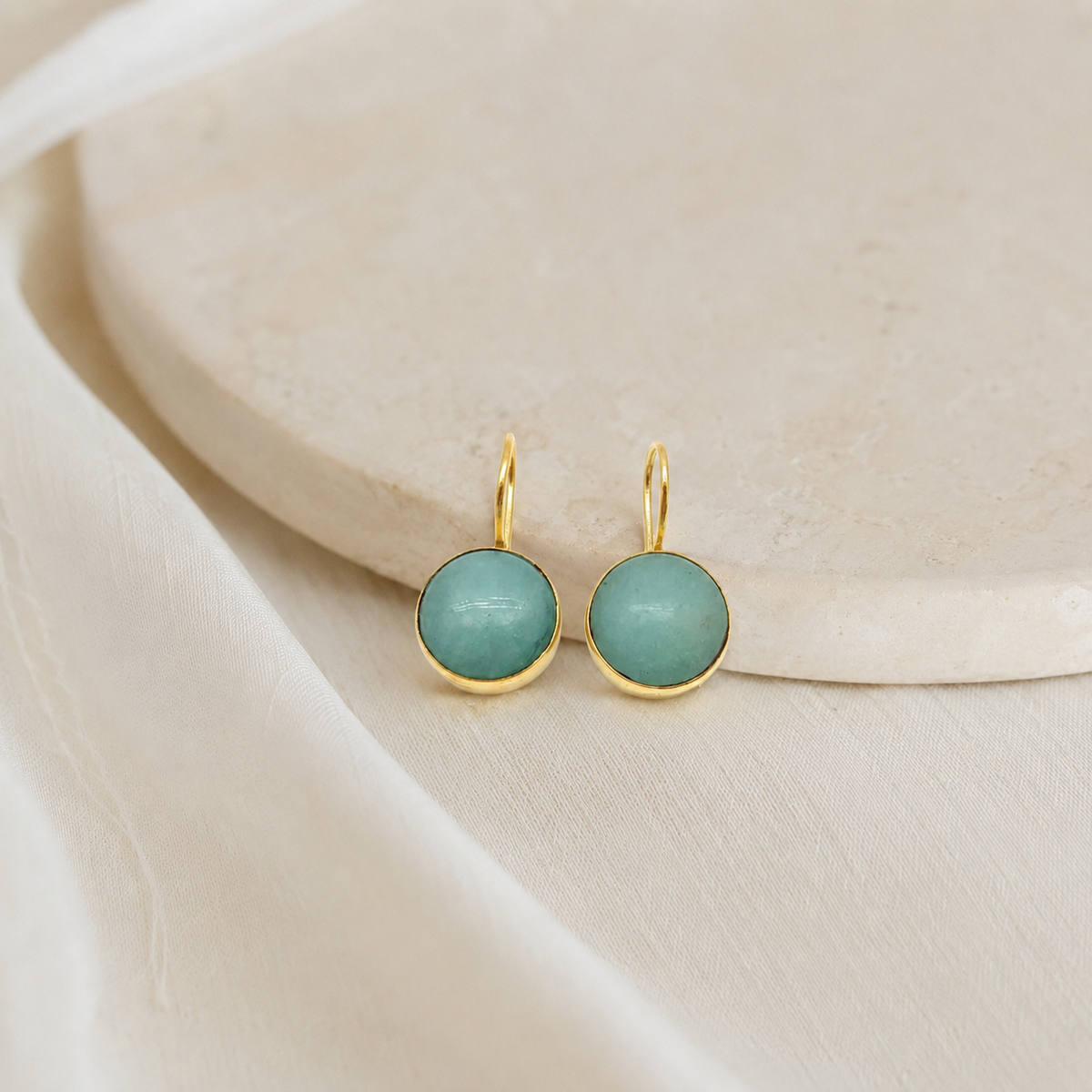 Clear quartz drop earrings with a rounded gold-plated frame.