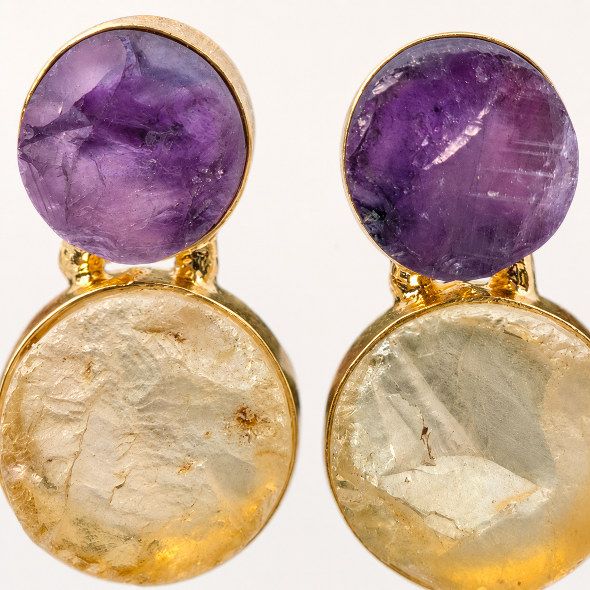 Detail view of textured amethyst and clear quartz drop earrings with gold-plated edges.