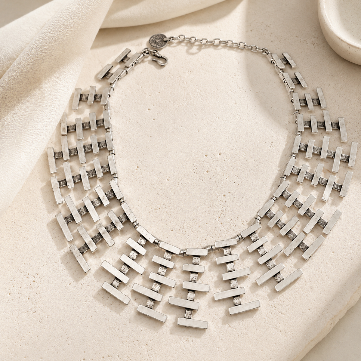 Silver-tone statement necklace with layered bar fringe styling.