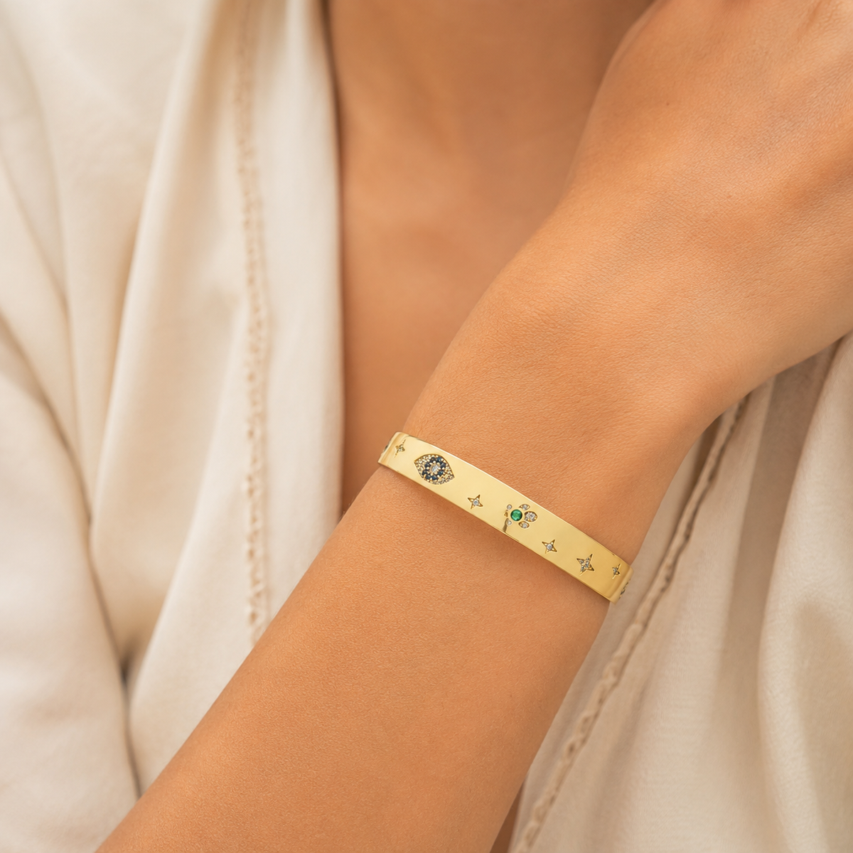 Gold-tone cuff bracelet shown from the front with decorative motifs.